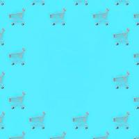 Shopping addiction, shopping lover or shopaholic concept. Many small empty shopping carts perform a pattern on a pastel colored paper background. Flat lay composition, top view photo