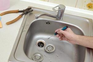 Close-up of handsome plumber hands repairing drain of kitchen sink photo