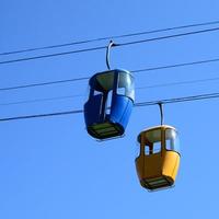 Blue and yellow passenger cable way cabins in the clear sky photo