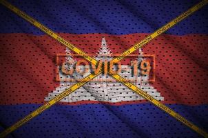 Cambodia flag and Covid-19 stamp with orange quarantine border tape cross. Coronavirus or 2019-nCov virus concept photo