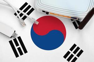 South Korea flag depicted on table with internet rj45 cable, wireless usb wifi adapter and router. Internet connection concept photo