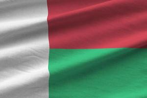 Madagascar flag with big folds waving close up under the studio light indoors. The official symbols and colors in banner photo