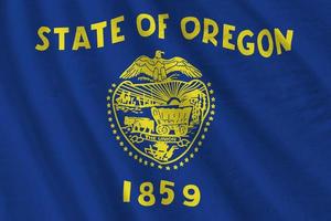 Oregon US state flag with big folds waving close up under the studio light indoors. The official symbols and colors in banner photo