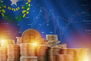Nevada US state flag and big amount of golden bitcoin coins and trading platform chart. Crypto currency photo