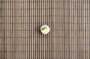 Sushi roll lie on a bamboo straw serwing mat. Traditional Asian food. Top view. Flat lay minimalism shot with copy space photo