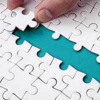 The human hand paves the way to the surface of the jigsaw puzzle, forming a blue space. The concept of overcoming the difficulties on the way to success photo