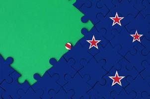 New Zealand flag  is depicted on a completed jigsaw puzzle with free green copy space on the left side photo