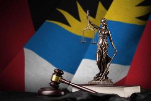 Antigua and Barbuda flag with statue of lady justice, constitution and judge hammer on black drapery. Concept of judgement and guilt photo