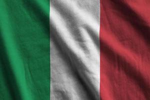 Italy flag with big folds waving close up under the studio light indoors. The official symbols and colors in banner photo