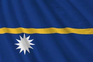 Nauru flag with big folds waving close up under the studio light indoors. The official symbols and colors in banner photo