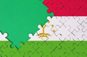 la bandera de tayikistán se representa en un rompecabezas completo con espacio de copia verde libre en el lado izquierdo foto