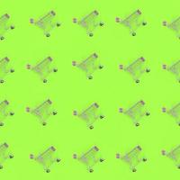 Shopping addiction, shopping lover or shopaholic concept. Many small empty shopping carts perform a pattern on a pastel colored paper background. Flat lay composition, top view photo