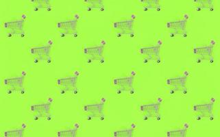 Shopping addiction, shopping lover or shopaholic concept. Many small empty shopping carts perform a pattern on a pastel colored paper background. Flat lay composition, top view photo