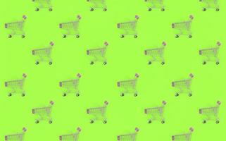 Shopping addiction, shopping lover or shopaholic concept. Many small empty shopping carts perform a pattern on a pastel colored paper background. Flat lay composition, top view photo