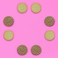 Frame of a brown biscuits on a pink background. Trendy minimal concept of food and dessert. Abstract flat lay, top view photo