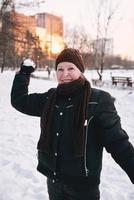 mujer mayor con sombrero y chaqueta deportiva bolas de nieve en el parque de invierno de nieve. invierno, edad, deporte, actividad, concepto de temporada foto