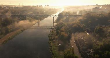 flight over the river in the morning mist, panoramic view of the railway bridge