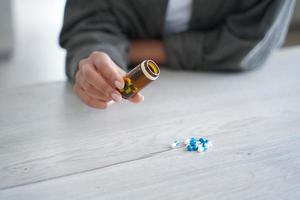 Female holds jar with medicines, pours pills on table, close up. Dietary supplement, vitamins, meds photo