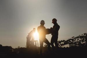 silhouette worker engineer looking blueprint in a building site over Blurred construction site film grain progress and potential personal and career growth concepts. photo