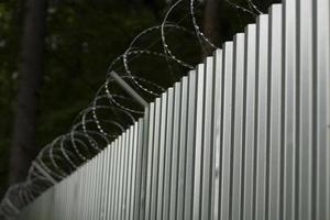 Steel fence with barbed wire. Fence around plant. Private territory. Metal profile. Dangerous wire. photo