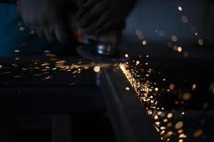 Sparks in dark. Metal grinding. Orange lights fly in different directions. Work in metal workshop. photo