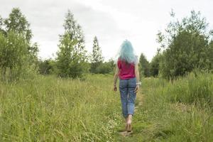 niña caminando sobre la hierba. hermosa mujer se aleja. vaqueros y velo en la cabeza. foto