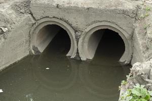 Sewer pipe. Canal with dirty water. Waste draining. photo