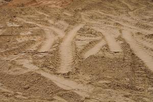 Tire track mark lines shape on dry sand background. Trail tyre imprint from heavy machinery. Vehicle shape. Road construction site backdrop concept. Trace of wheel pattern on mud. Nature texture. photo