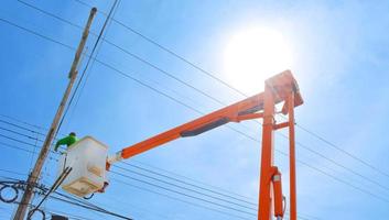 Man, worker on top of crane tractor for maintenance electric cables without safety belt is risk work. Concept of unsafe work place, risk work, unsafe work. photo