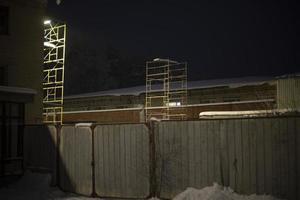 Industrial area at night. Building is in dark. Gates and fence in dark. photo