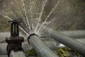 Valve on tube. Torn pipe valve. Boiling water pours from pipeline. photo