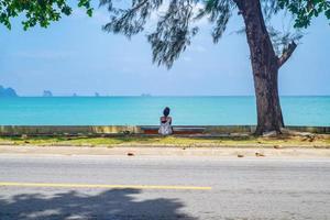 Unacquainted Woman sitting beside Ao nang beach with beautiful seascape and Endless horizon in krabi city Thailand.Krabi - in southern Thailand is one of the most relaxing places on the planet photo