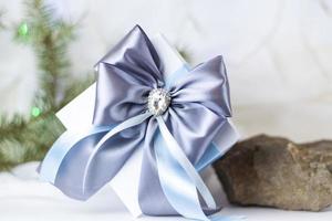 A Christmas gift decorated with a beautiful bow on a light background with a fir twig. Gifts, joy, surprise. Selective focus. the concept of Christmas and New Year. photo