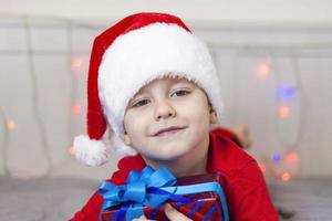 Portrait of a cute boy in a Santa Claus hat. Funny smiling child. Gifts, toys, joy, celebration. photo