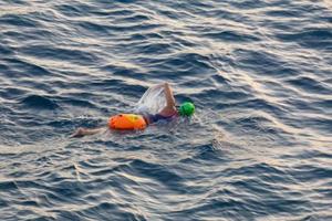 Swimmer swimming in open water in the Mediterranean Sea with a safety buoy photo