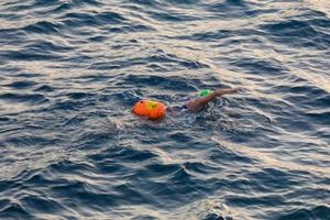 Swimmer swimming in open water in the Mediterranean Sea with a safety buoy photo