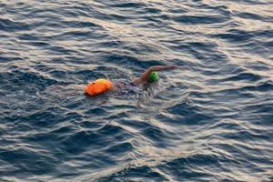 Swimmer swimming in open water in the Mediterranean Sea with a safety buoy photo