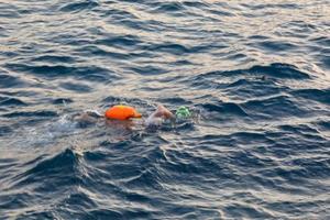 Swimmer swimming in open water in the Mediterranean Sea with a safety buoy photo
