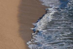 Foam from the waves as they reach the sand on the beach photo