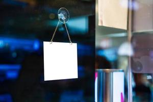 Empty white signboard hanging on glass window in shopping store photo