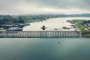 Traditional Mon village in morning foggy and wooden Mon bridge in the dam at Sangkhlaburi photo