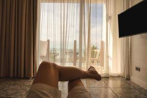 Man relaxing cross legged in bedroom with sunshine through curtain in the morning photo