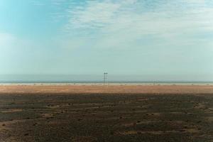 poste de electricidad de madera y el cielo en el desierto remoto cerca del mar en el campo foto