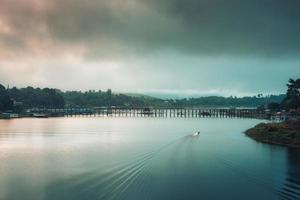 View of boat paddling on Songkalia river and Mon wooden bridge in the monring at Sangkhlaburi photo