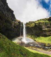 Rainbow on Kvernufoss waterfall hidden in mossy rocky gorge on summer at Iceland photo