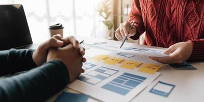 grupo de lluvia de ideas de concepto de trabajo de personas. lluvia de ideas del equipo de negocios. investigación del plan de marketing. papeleo en la mesa, computadora portátil y teléfono móvil. foto