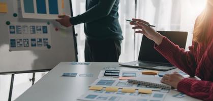 Ux developer and ui designer brainstorming about mobile app interface wireframe design on table with customer breif and color code at modern office.Creative digital development agency photo