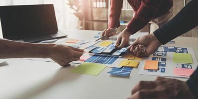 Close up ux developer and ui designer brainstorming about mobile app interface wireframe design on table with customer breif and color code at modern office.Creative digital development agency photo