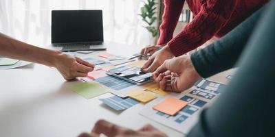 Close up ux developer and ui designer brainstorming about mobile app interface wireframe design on table with customer breif and color code at modern office.Creative digital development agency photo