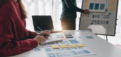 Ux developer and ui designer brainstorming about mobile app interface wireframe design on table with customer breif and color code at modern office.Creative digital development agency photo